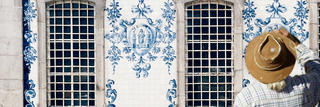Junger portugiesischer Handwerker bemalt eine traditionelle blau-weiße Azulejo-Wand – steht sinnbildlich für die Weitergabe von Handwerkskunst und kulturellem Erbe in Portugal.