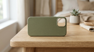 Eine elegante, pflanzenbasierte Premium-Handyhülle in sanften Naturtönen, arrangiert auf einem minimalistischen Holztisch.