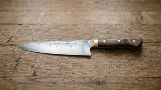 Nahaufnahme eines handgefertigten Messers, das die Maserung des Holzgriffs und die feine Politur der Klinge zeigt.