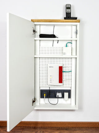 Bild mit Telefonschrank LOLE HomeBase an der Wand, Router und Telefon ordentlich im Schrank verstaut, Kabel sauber geführt, moderner Flur-Hintergrund, klare Linien und funktionales Möbeldesign.
