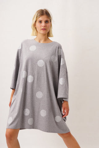 Unisex Oversize-Bigshirt aus 100 % Baumwolle mit großen Glitter Dots allover, als kurzes Kleid getragen, im Licht funkelnd, frontal vor neutralem Hintergrund fotografiert.
