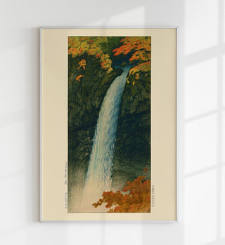 Vertikale Landschaftsdarstellung des Kegon-Wasserfalls bei Nikko im Stil von Kawase Hasui, schmaler Wasserstrahl vor hohen Felswänden, umgeben von Vegetation, als Fine-Art-Poster gerahmt an einer hellen Wand in einem ruhig eingerichteten Raum
