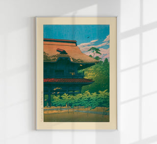 Ansicht des Kenchō-ji-Tempels in Kamakura im Stil von Kawase Hasui, Tempeldächer eingebettet in grüne Hügel und Bäume unter weichem Himmel, als Fine-Art-Poster gerahmt an einer hellen Wand in einem dezent eingerichteten Wohn- oder Arbeitsraum
