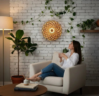 Gofurnit Veneria lampshade made of amber wood, featuring a spiral design and warm, natural wood tones. Mounted on a white brick wall with green vines.