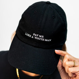 pay me like a white man unisex dad cap in schwarz mit weißer Schrift am Model