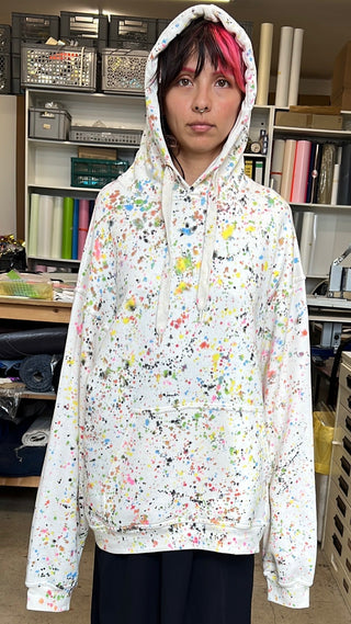 Unisex Hoody mit relaxed Fit, handbemalten Drip- und Splash-Farbflächen im Jackson-Pollock-Stil, frontal fotografiert, wirkt wie eine farbexplosive, tragbare Leinwand.
