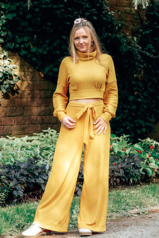 Weite gelbe High-Waist-Hose aus weichem Rippenjersey mit elastischem Bund und locker fallendem Bein, ideal für herbstliche Outfits und gemütliche Waldspaziergänge
