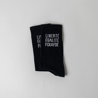 Liberté. Égalité. FCKAFDÉ Statement Socken in schwarz vor weißem Hintergrund