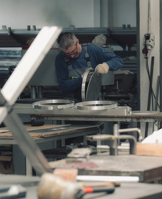 Montage eines Metallrands an einer Tischplatte durch Mitarbeiter in der Siqual Design Manufaktur