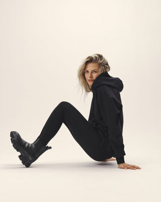 Oversized Damen Hoodie aus Organic Cotton in Schwarz, getragen von Model in sitzender Position