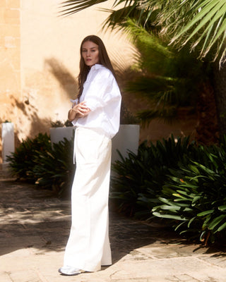 Kurze Damen Hemdbluse in Weiß aus Bio-Baumwolle von WOTE, seitlich am Model getragen, Editorial Outdoor Aufnahme.