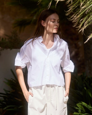 Kurze Damen Hemdbluse in Weiß aus Bio-Baumwolle von WOTE, locker geschnitten und am Model getragen, Outdoor Editorial Aufnahme.