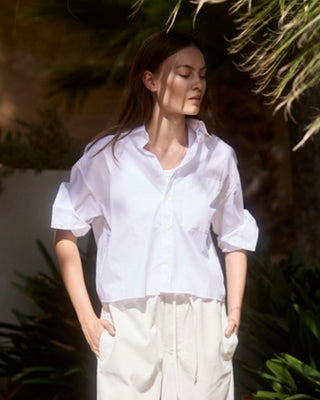Kurze Damen Hemdbluse in Weiß aus Bio-Baumwolle von WOTE, locker geschnitten und am Model getragen, Outdoor Editorial Aufnahme.