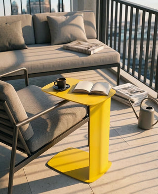 C-förmiger Beistelltisch STANDBY aus Aluminium von Siqual Design in Gelb neben Sessel auf dem Balkon