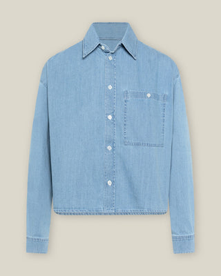 Hellblaue, kurz geschnittene Denimbluse aus Bio-Baumwolle in Frontansicht mit klassischem Kragen, Knopfleiste und Brusttasche.