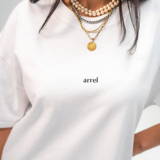 Nachaufnahme des arrel unisex oversized t-shirt weiß mit arrel design auf der brust am weiblichen Model 