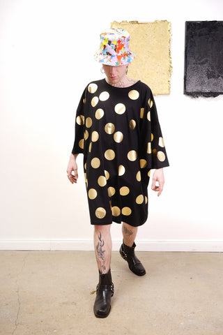 Unisex Oversize-Bigshirt mit glänzendem Allover-Punkte-Print vor hellem Hintergrund, frontal aufgenommen, locker fallend auf einem Model im urbanen Umfeld.
