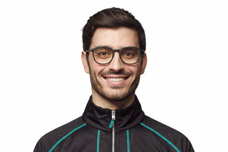 Smiling man in stylish eyewear wearing a black zip-up tracksuit jacket with teal stripes, showcasing trendy men's athletic apparel.