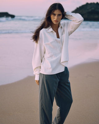 Offwhitefarbenes Cord Hemd für Damen aus Bio-Baumwolle mit lockerem Schnitt, getragen in ruhiger Ganzkörperansicht am Strand.