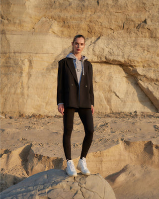 Schwarze Damen Leggings aus Organic Cotton und Modal von WOTE, getragen von einem Model im Outdoor-Setting mit Blazer und Hoodie, natürliche Passform mit hohem Bund.