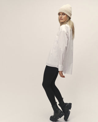 Schwarze Damen Leggings aus Organic Cotton und Modal von WOTE, seitliche Ansicht mit leicht gedrehter Pose im Studio, schmale Beinführung und hoher Bund.