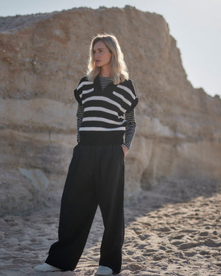 Schwarz-weiß gestreiftes Damen Longsleeve aus Bio-Baumwolle von WOTE, Frontansicht am Model in natürlicher Strandlandschaft.