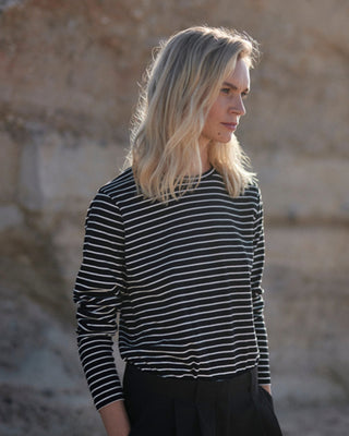 Schwarz-weiß gestreiftes Damen Longsleeve aus Bio-Baumwolle von WOTE, Seitenansicht am Model im natürlichen Outdoor-Look.