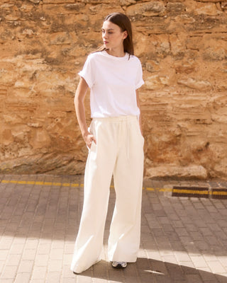 Weißes Relaxed-Fit Rundhals-T-Shirt aus Bio-Baumwolle für Damen, getragen von einem Model im sommerlichen Balearic Look.