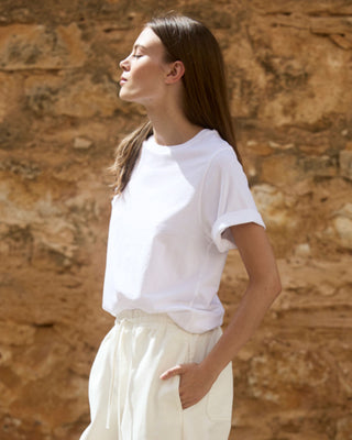 Weißes Relaxed-Fit Rundhals-T-Shirt aus Bio-Baumwolle für Damen, Seitenansicht an einem Model im sommerlichen Look.