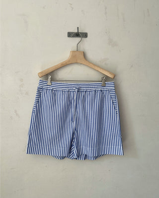 Blau-weiß gestreifte Damen Shorts aus Bio-Baumwolle von WOTE, aufgehängt an einem Holzkleiderbügel vor neutralem Hintergrund.