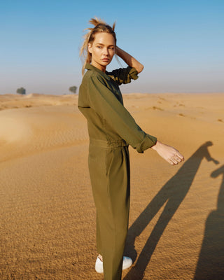 Olivfarbener Damen Utility Overall aus Bio-Baumwolle von WOTE, Seitenansicht im Outdoor-Setting mit lockerem Schnitt und Taillenband.