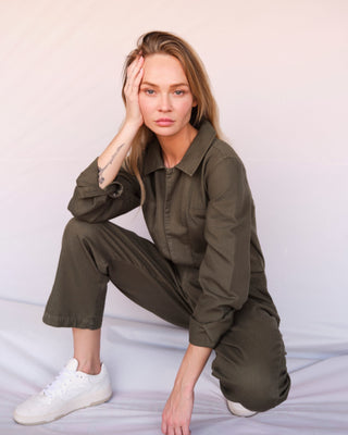 Olivfarbener Damen Utility Overall aus Bio-Baumwolle von WOTE, sitzende Studioaufnahme mit lockerem Schnitt und umgeschlagenen Ärmeln.