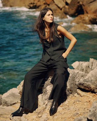 Schwarze Damenweste aus nachhaltiger Tuchwolle, kombiniert mit weiter schwarzer Hose in kraftvollem Editorial-Look.