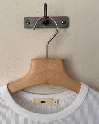 Detailansicht des weißen gerippten Damen T-Shirts aus Bio-Baumwolle mit WOTE-Label am Halsausschnitt auf Holzbügel.