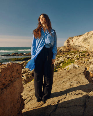 Kurz geschnittenes Hemdblusenkleid aus Bio-Baumwolle für Damen in Blau, locker getragen in Bewegung mit fließendem Stofffall.
