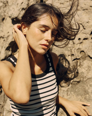 Detailaufnahme des offwhite-schwarz gestreiften Damen Tanktops in New-Shape-Passform aus Bio-Baumwolle mit höherem Rundhalsausschnitt von WOTE, am Model vor Felslandschaft