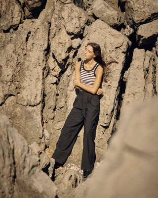 Offwhite-schwarz gestreiftes Damen Tanktop in New-Shape-Passform aus Bio-Baumwolle mit höherem Rundhalsausschnitt von WOTE, am Model vor Felslandschaft getragen